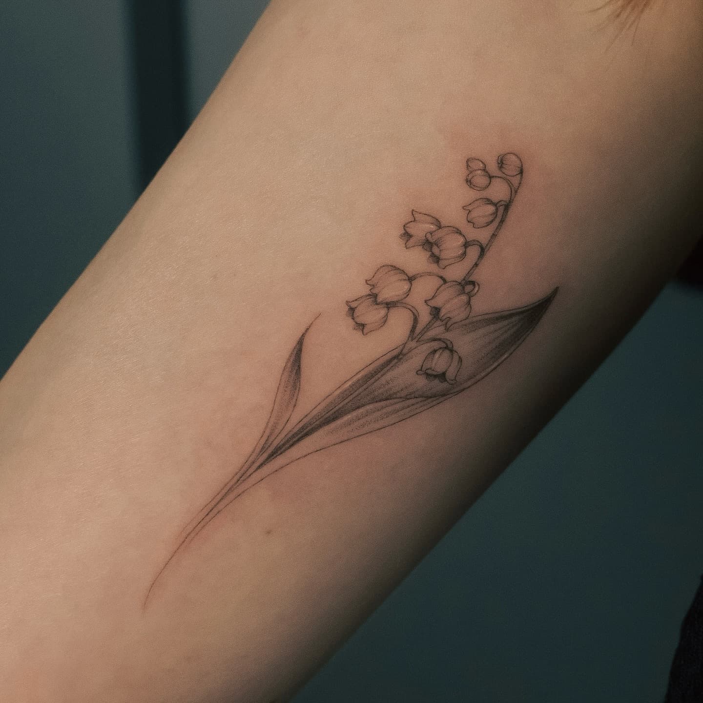 Konwalia na ramieniu – tatuaż fine line